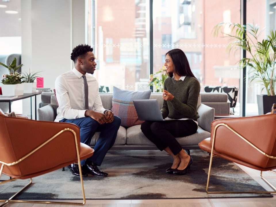 Businesswoman Interviewing Male Job Candidate In Seating Area Of Modern Office