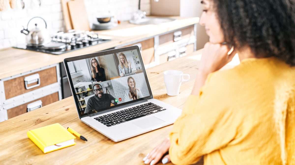 Une femme assiste à un appel vidéo sur ordinateur portable avec quatre collègues