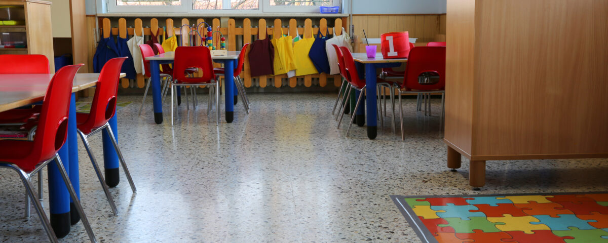 Small desks and chairs inside an empty daycare classroom